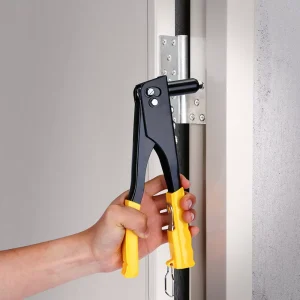 Heavy Duty Pop Rivet Gun being used to install a metal door hinge. This manual hand riveter kit features ergonomic yellow handles and a black steel head, ideal for professional automotive and DIY metalwork repair.