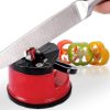 Professional Knife Sharpener with Power Grip suction base being used to sharpen a stainless steel chef knife, featuring tungsten carbide sharpening blades and a red non-slip body next to sliced bell peppers