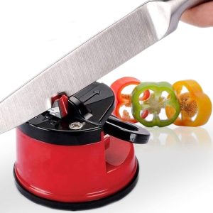 Professional Knife Sharpener with Power Grip suction base being used to sharpen a stainless steel chef knife, featuring tungsten carbide sharpening blades and a red non-slip body next to sliced bell peppers