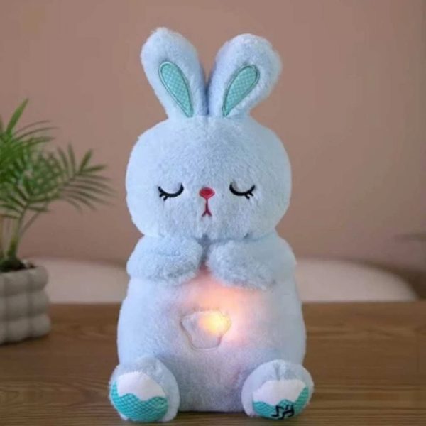 The Plush Breathing Cute Rabbit Toy is a light blue sensory plush bunny sitting upright with embroidered sleeping eyes, teal patterned inner ears and footpads, and a warm glowing light on its belly.
