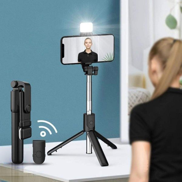 The black R1S Selfie Stick with Integrated Flash and Multi-Color Light is shown expanded as a tripod holding a smartphone with an illuminated top fill light, alongside a wireless remote control and its compact folded state.